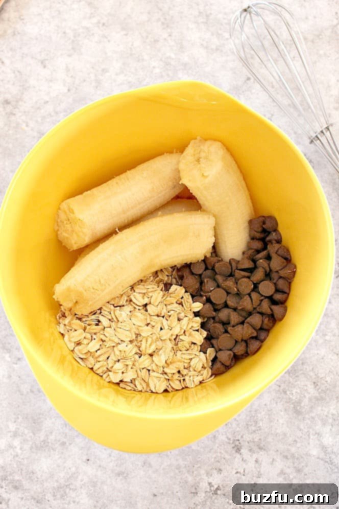 3 Ingredient Oatmeal Chocolate Chip Cookies Recipe - healthy cookies made with bananas, old-fashioned oats and chocolate chips. Bananas, oats, and chocolate chips in a yellow mixing bowl