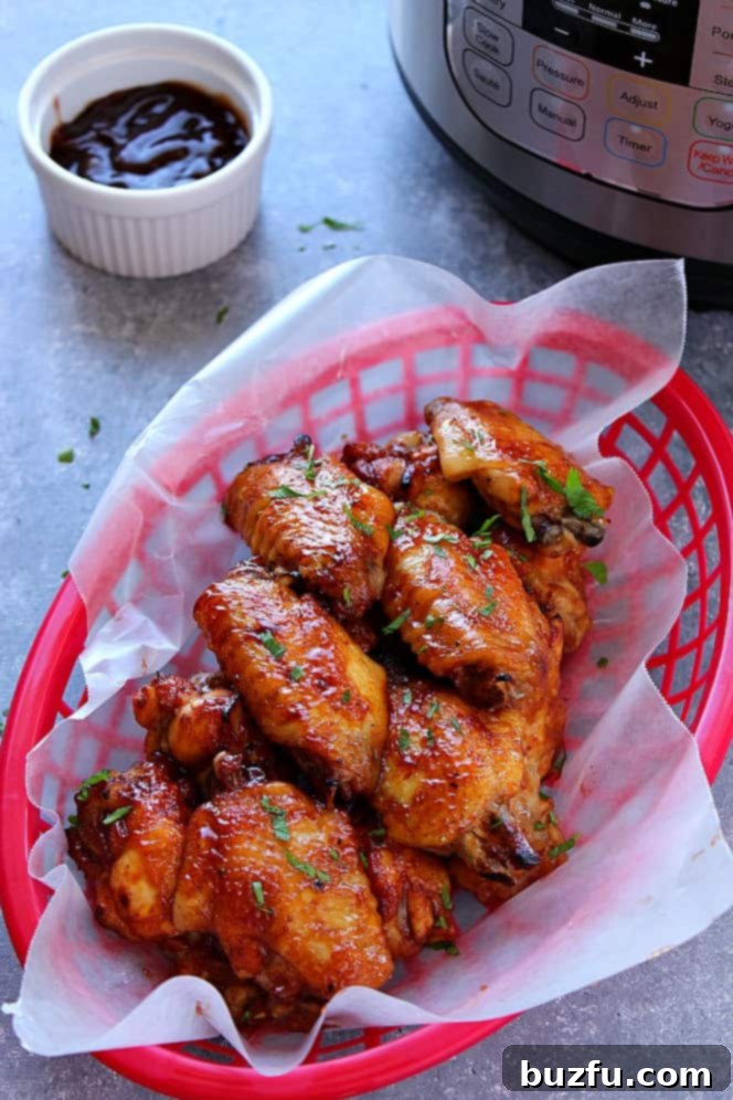 Instant Pot BBQ Chicken Wings Recipe - Juicy chicken wings with sweet and spicy rub, cooked to perfection in the Instant Pot, then coated in rich BBQ sauce and broiled for crispy skin. Perfect for your next Summer potluck party! A vibrant pile of Instant Pot BBQ Chicken Wings, glazed and crispy, presented in a red serving basket. Perfect for a summer potluck party.