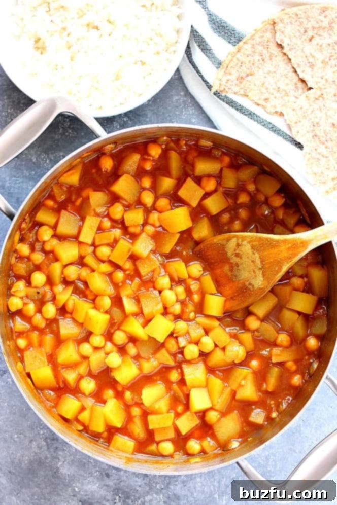 Easy Chickpea and Potato Curry cooking in a stainless steel pan, showcasing the rich, saucy texture