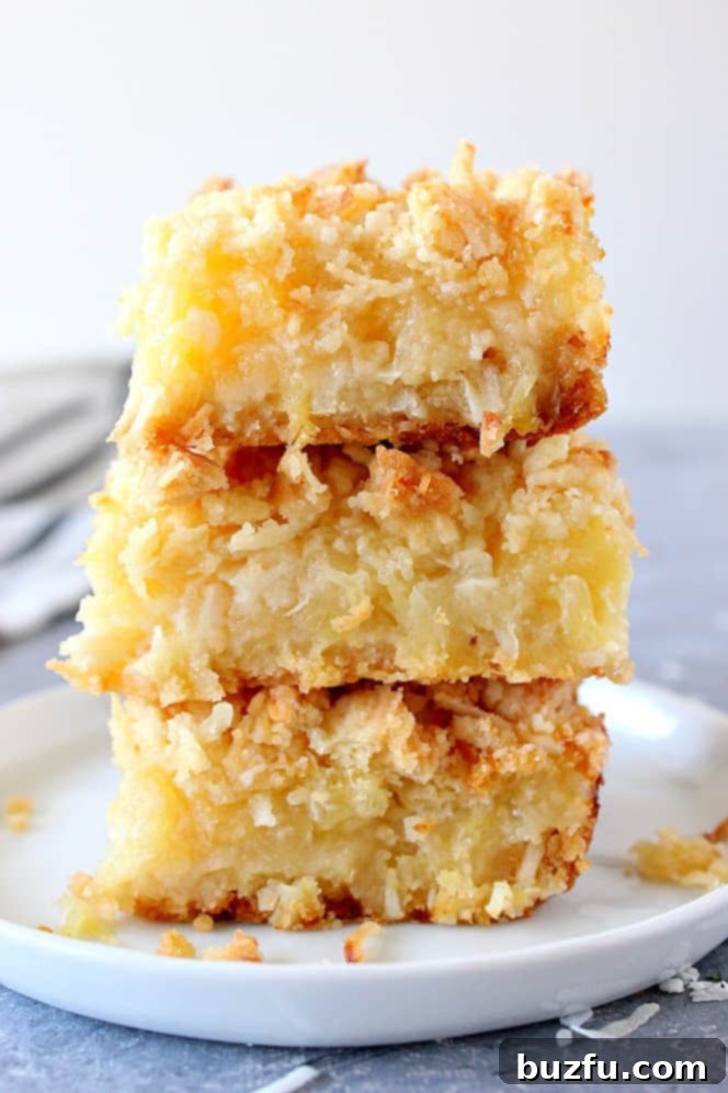 Close up on golden pineapple coconut bars stacked elegantly on a white plate, showcasing their crumbly topping and vibrant fruity filling. Perfect for a tropical dessert.