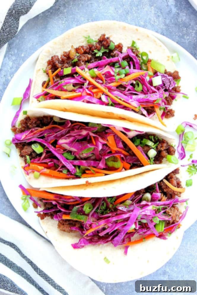 Three Korean Beef Tacos with a side of colorful Asian slaw on a white plate, ready to be served.