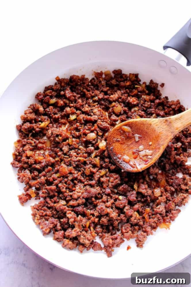 Ground beef being cooked and coated in a rich Korean sauce in a white pan.
