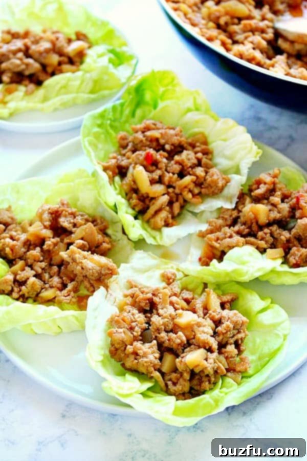 P. F. Chang's Chicken Lettuce Wraps - ground chicken is cooked in Asian hoisin sauce and served on lettuce cups for a perfect meal. Delicious P.F. Chang's Chicken Lettuce Wraps served on a pristine white plate, showcasing the vibrant filling and fresh lettuce cups.