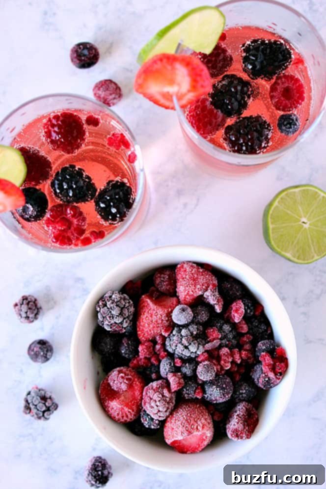 Overhead shot of frozen berries in white bowl with two glasses of sangria on the side.