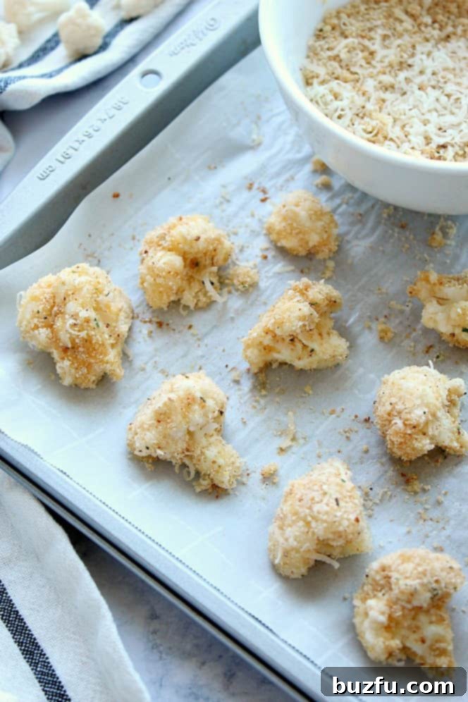 Side shot of breaded cauliflower florets on baking sheet.