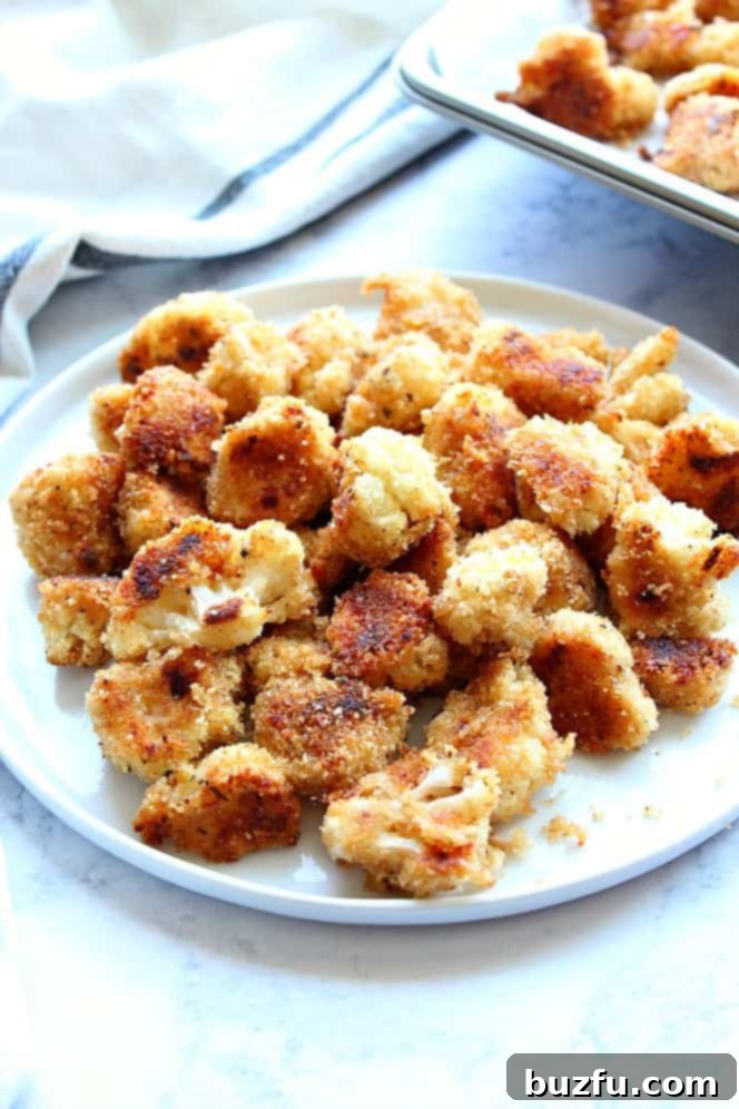 Side shot of roasted breaded cauliflower bites on white plate. 