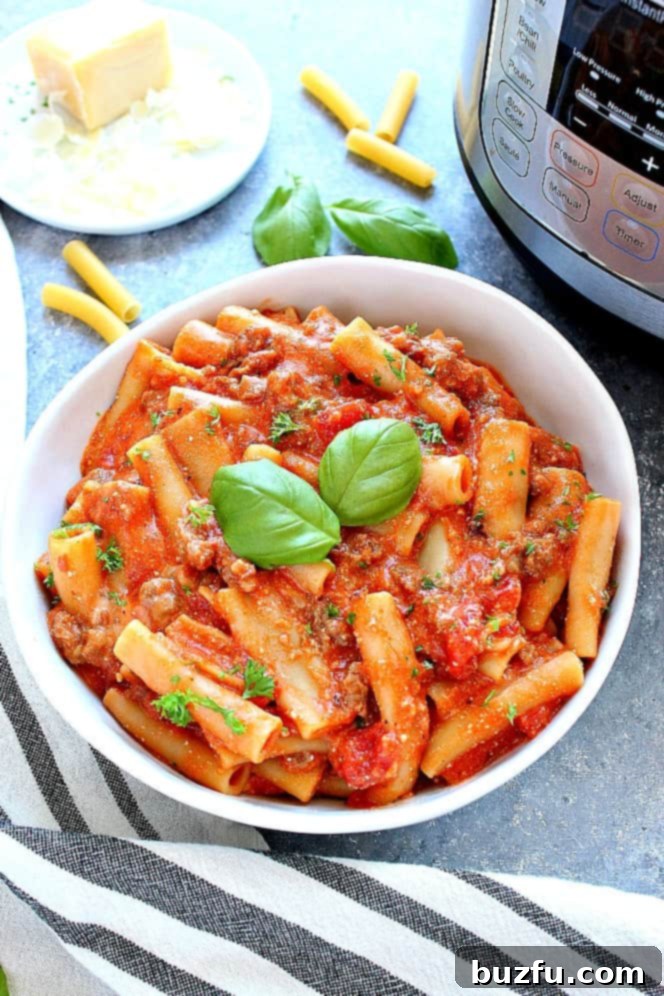 Side shot of ziti pasta in white pasta bowl next to Instant Pot. 