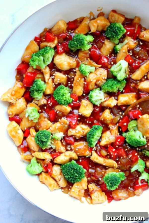 Teriyaki chicken stir fry in a white skillet, garnished with fresh sesame seeds and green onions.