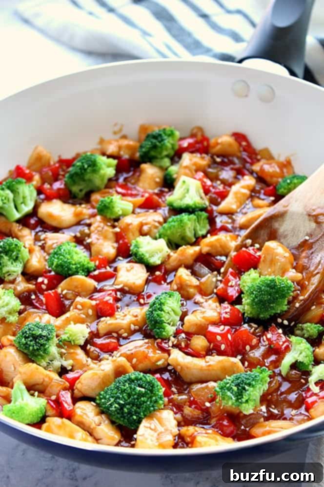 Close-up side view of a white pan filled with vibrant Teriyaki Chicken Stir Fry, showing tender chicken, bell peppers, and bright green broccoli.