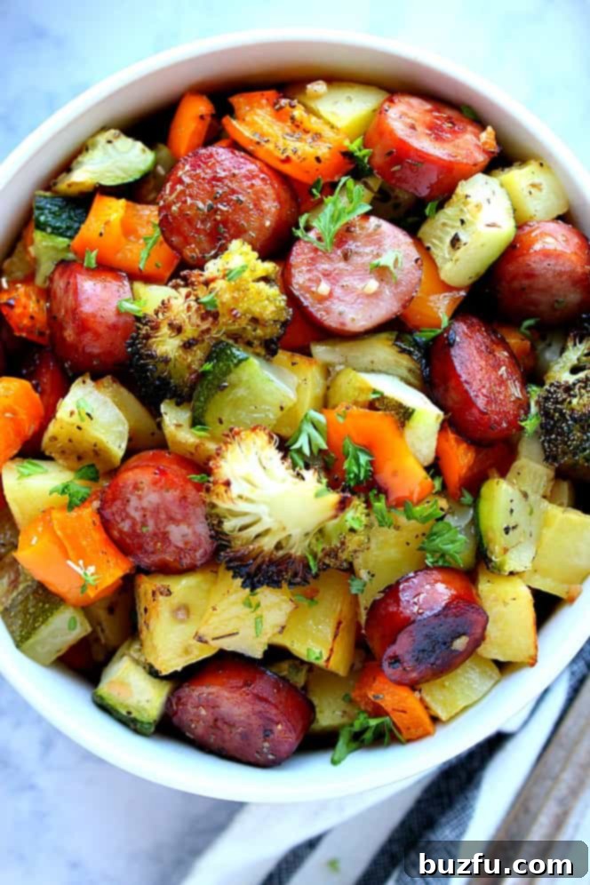 Overhead shot of roasted vegetables and sausage in white bowl. 