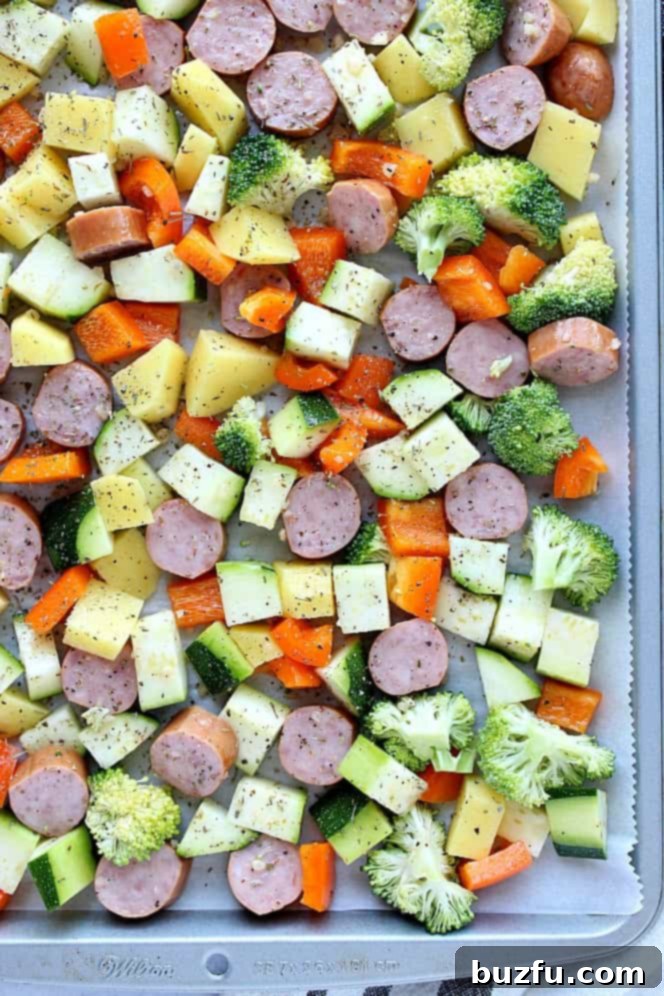 Overhead shot of baking pan with sausage, potatoes, broccoli, peppers and zucchini. 