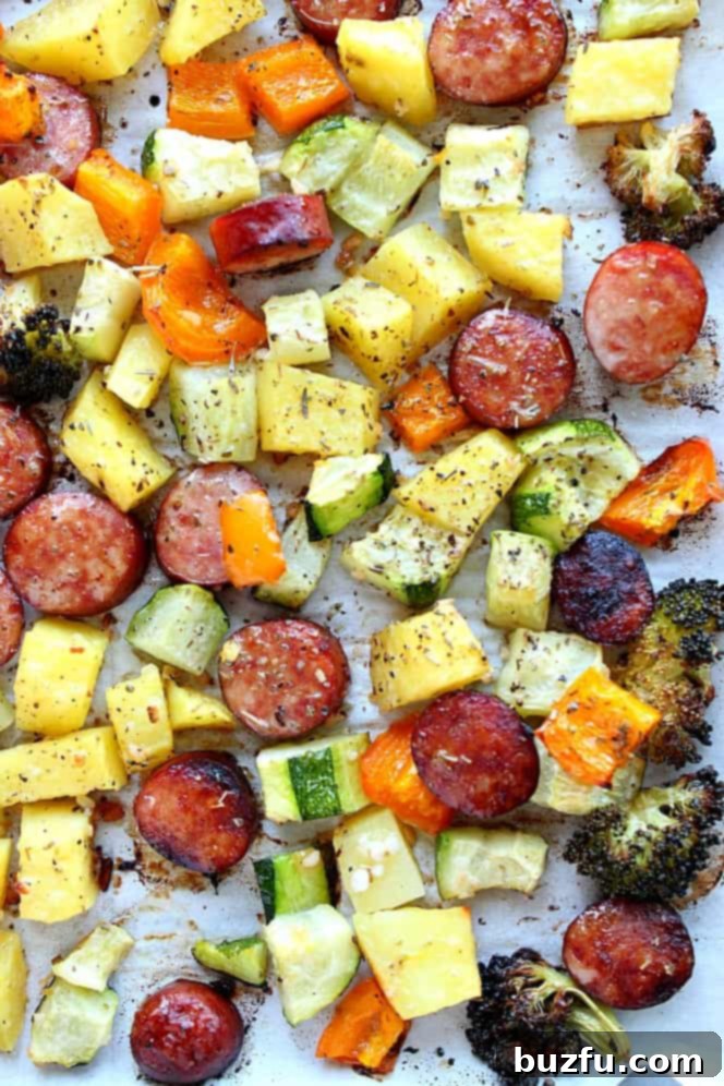Overhead close up shot of roasted vegetables and sausage on sheet pan.