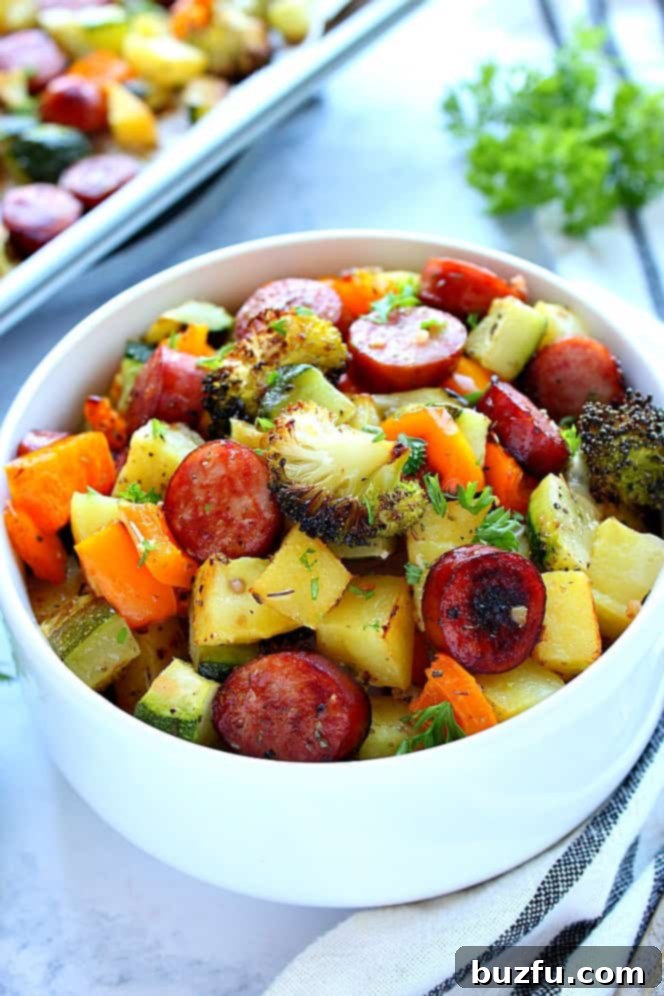 Side shot of white bowl filled with roasted sausage and vegetables. 