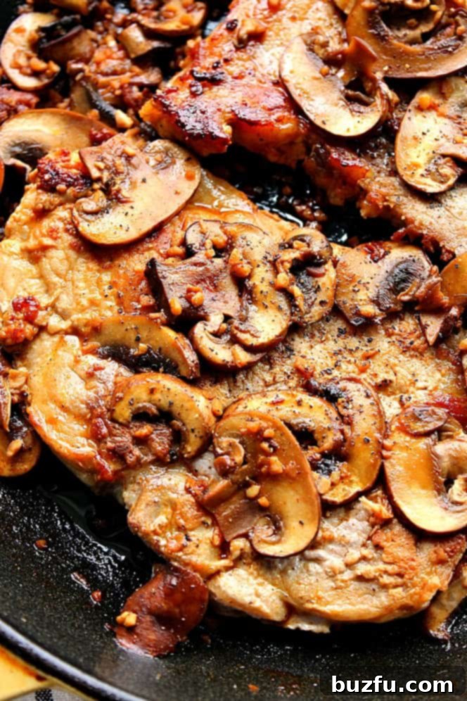 Close-up overhead shot of perfectly seared garlic butter mushroom pork chops in a cast iron skillet, ready to serve.