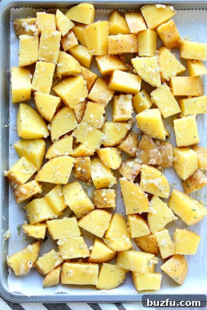 Garlic Ranch Roasted Potatoes Recipe - perfectly roasted potatoes with garlic and Ranch seasoning and a mix of butter and oil for the best roasting result. Simple vegetable turned into one delicious side dish! Chopped golden potatoes spread in a single layer on a parchment-lined baking sheet, seasoned and ready for roasting.