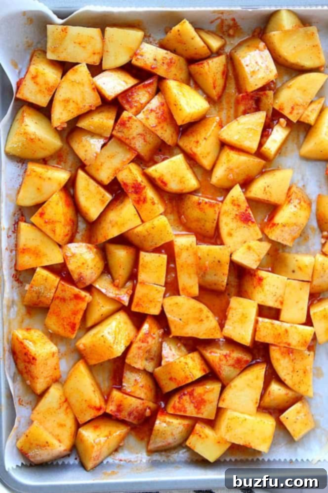 Easy Oven Roasted Potatoes Recipe - crispy on the outside and soft on the inside, these roasted potatoes are the easiest side dish ever! Overhead shot of potatoes coated with paprika butter on a baking sheet.