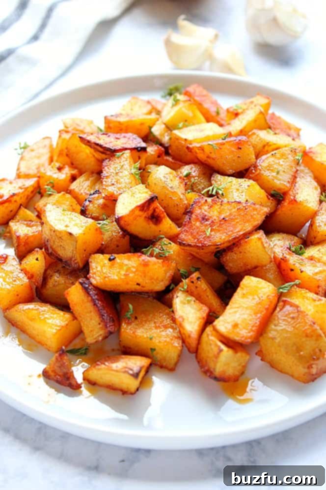 Easy Oven Roasted Potatoes Recipe - crispy on the outside and soft on the inside, these roasted potatoes are the easiest side dish ever! Side shot of golden roasted potatoes on white plate, garnished with parsley.