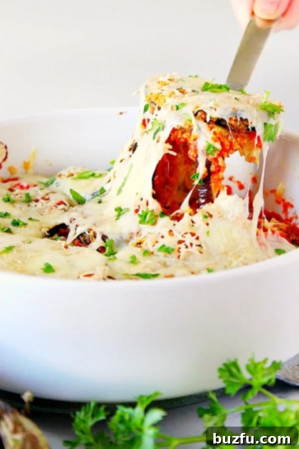 Baked Eggplant Parmesan Recipe - no mess, no fuss eggplant Parmesan with crispy garlic Parmesan breaded eggplant baked in the oven, not fried. Baked Eggplant Parmesan in white baking dish.