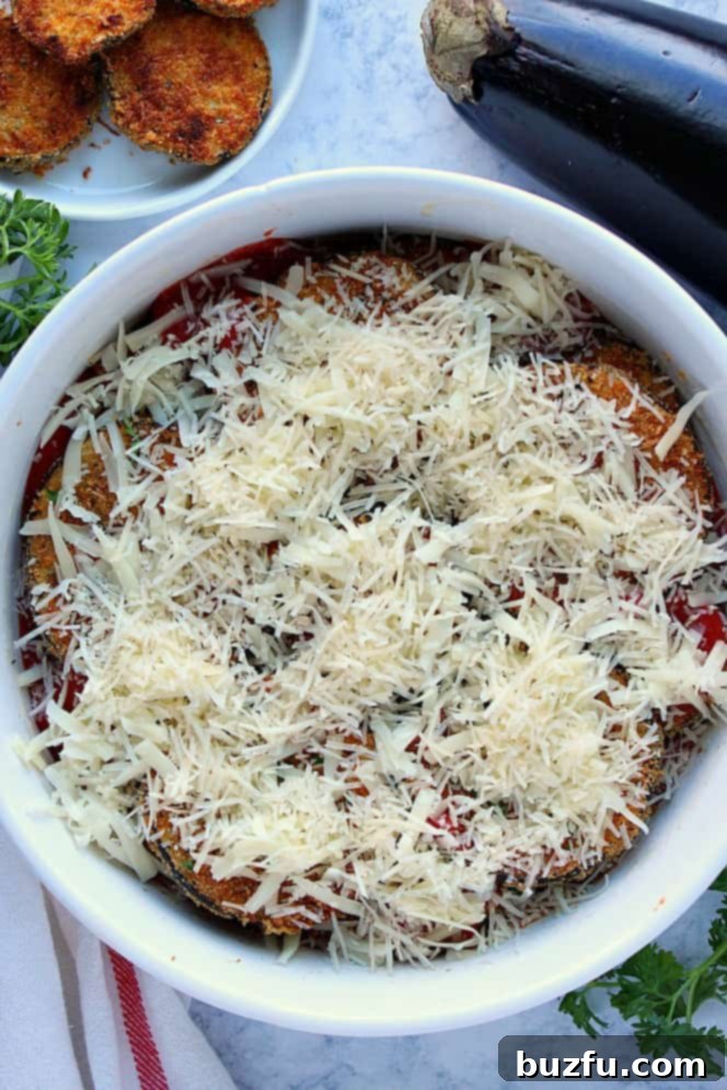 How to make healthy eggplant Parmesan casserole. Overhead shot of eggplant Parmesan topped with cheese, right before baking.