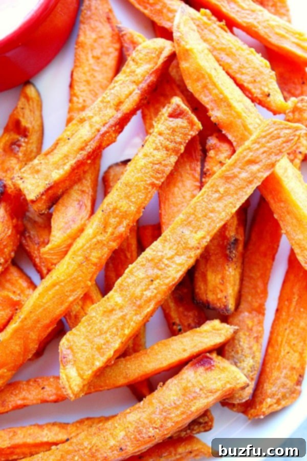 Crispy, golden, and healthy baked Sweet Potato Fries - a perfect side dish or snack. Overhead close up shot of sweet potato fries on white plate, perfectly golden and crispy.