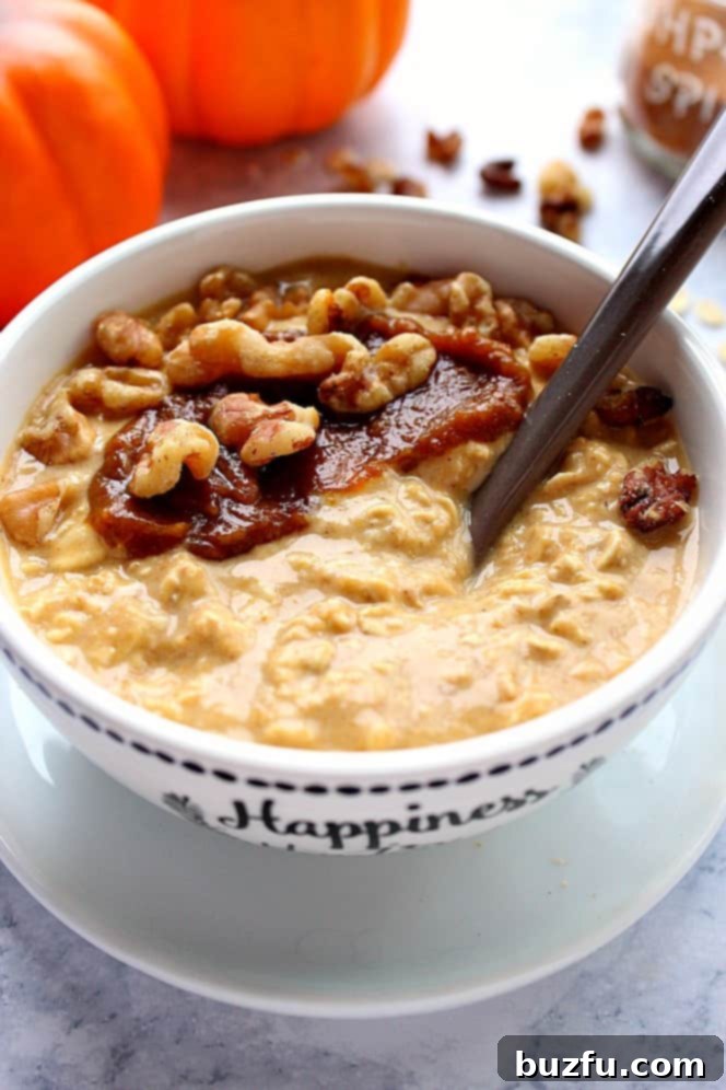 Side shot of pumpkin pie overnight oats with pumpkin butter and nuts in a white bowl, ready to be enjoyed.