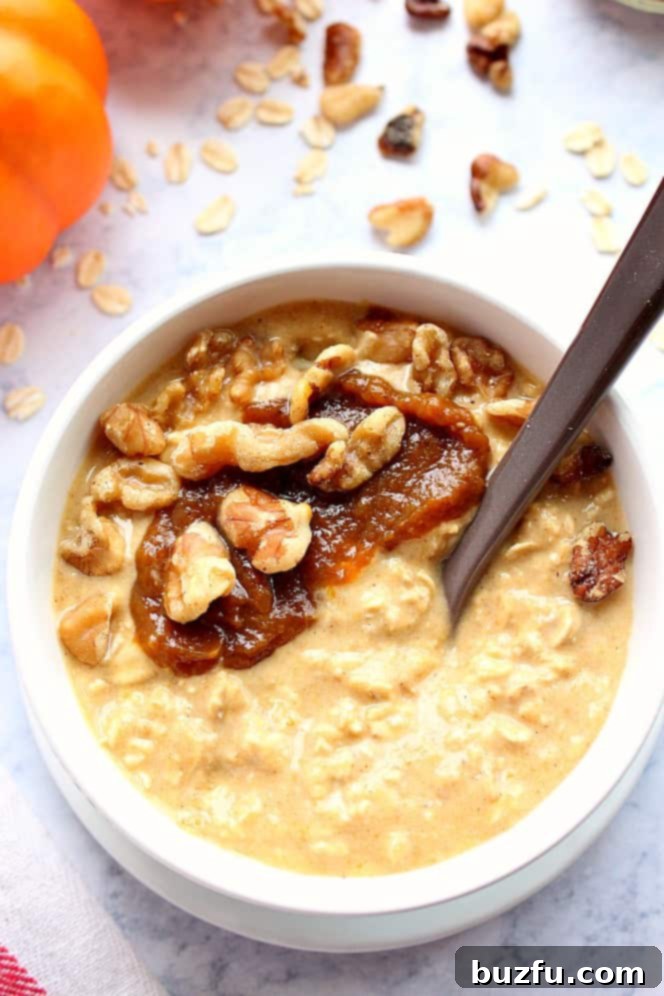 Overhead shot of pumpkin pie overnight oats in white bowl, with pumpkin butter and nuts on top, showcasing the inviting presentation.