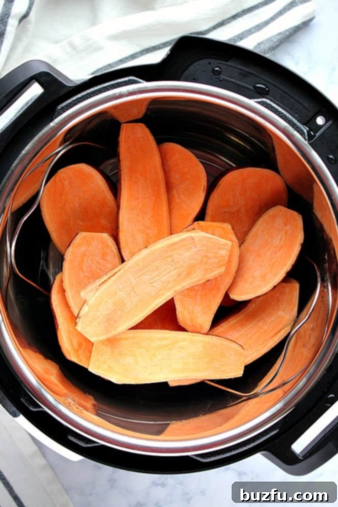 Overhead shot of sweet potatoes sliced in half, stacked on a metal trivet inside the Instant Pot, ready for cooking.