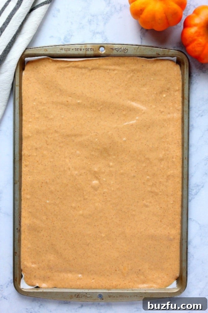 Pumpkin Sheet Pan Pancakes Recipe - soft, fluffy and filled with pumpkin and pumpkin spice pancakes baked in the oven on a sheet pan. No more flipping! Serve with spiced brown sugar butter. Overhead shot of pancake batter in large sheet pan.