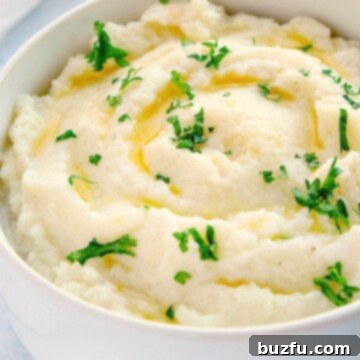 Mashed cauliflower in a white bowl, garnished with herbs.