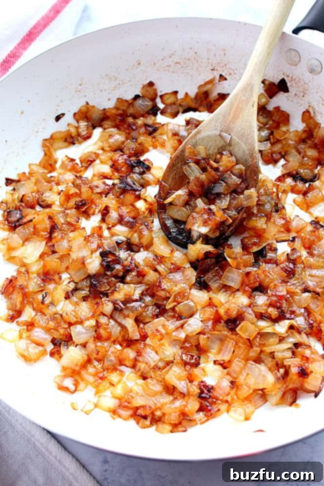 How to caramelize onions for a dip. Overhead close up shot of caramelized golden brown onions in white pan.