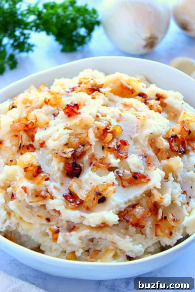 Caramelized Onions Mashed Potatoes Recipe - A Gourmet Twist A side shot of creamy mashed potatoes generously topped with glistening caramelized onions, served in an elegant white bowl, inviting a delightful culinary experience.