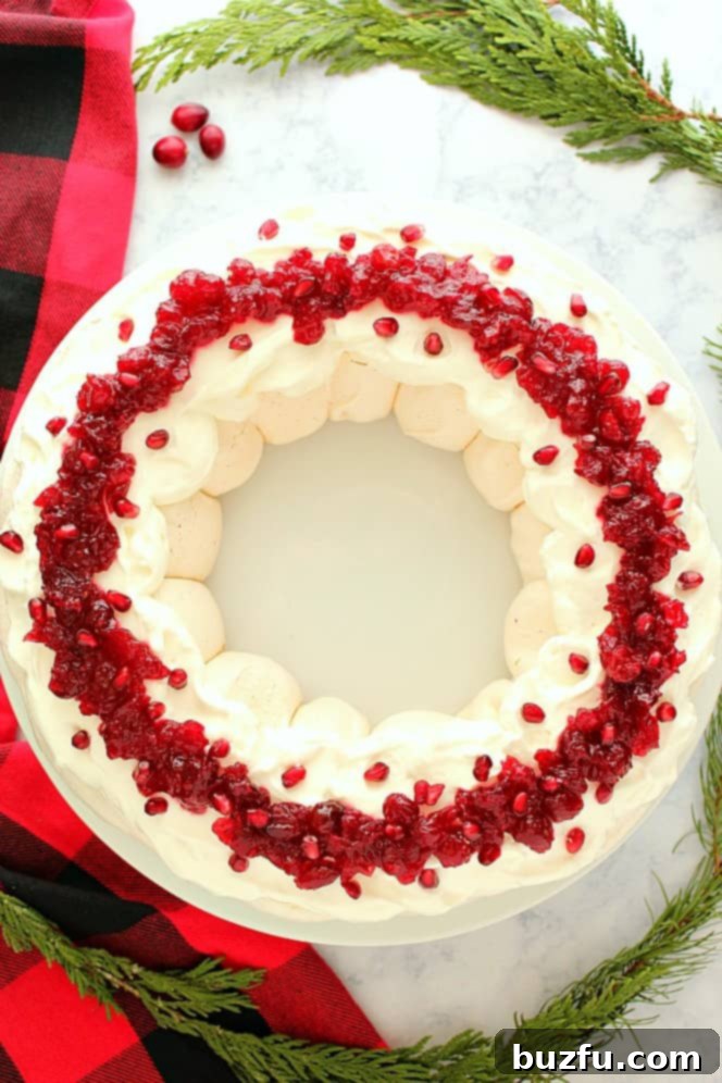 Overhead shot of a stunning Christmas Pavlova wreath, generously topped with fluffy whipped cream, vibrant cranberry sauce, and glistening pomegranate arils.