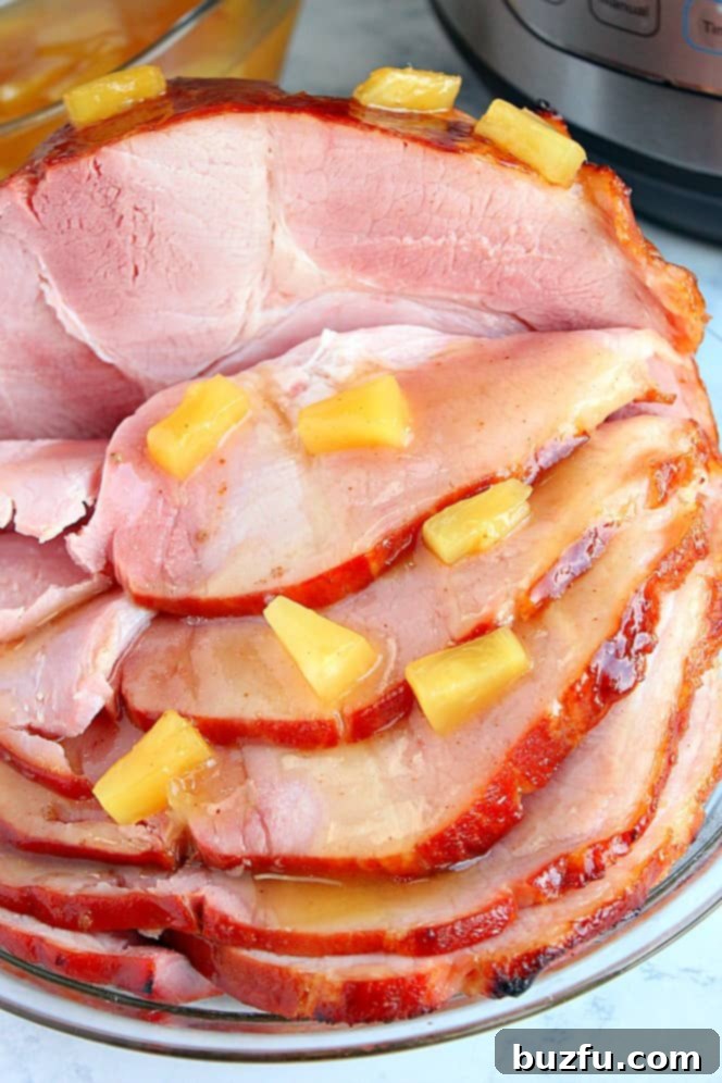 Side shot of sliced ham with pineapple chunks, glistening with a rich glaze.