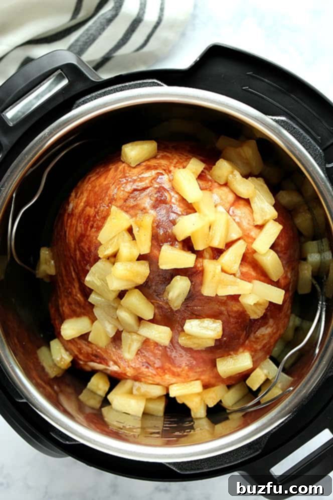 Overhead shot of ham with pineapple chunks in the Instant Pot, showing the cooking process.
