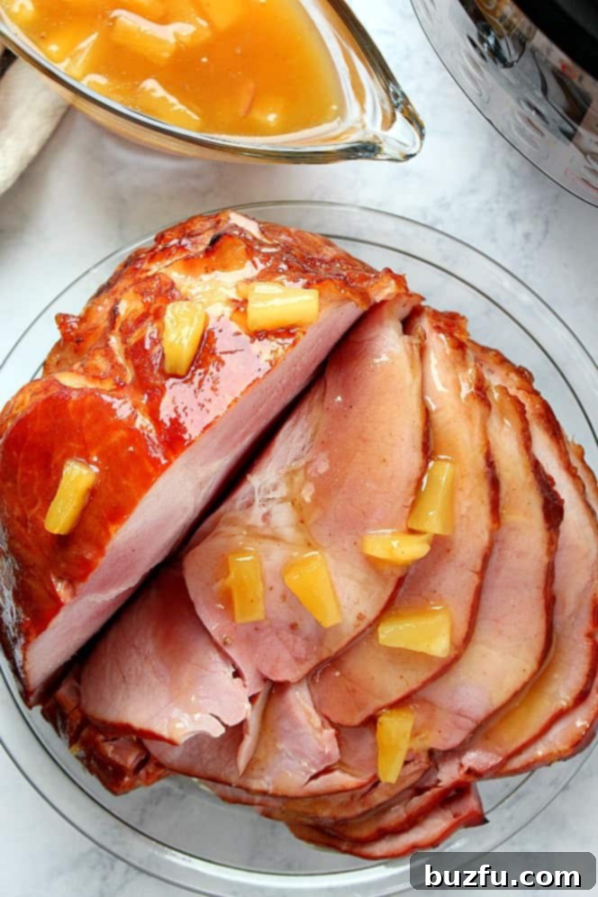 Overhead shot of sliced ham in a glass dish, with a gravy boat of glaze and the Instant Pot in the background.