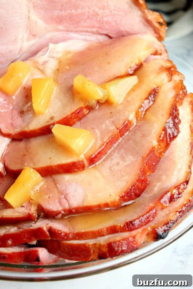 Close up shot of juicy sliced ham with pineapple chunks, coated in a sticky glaze.