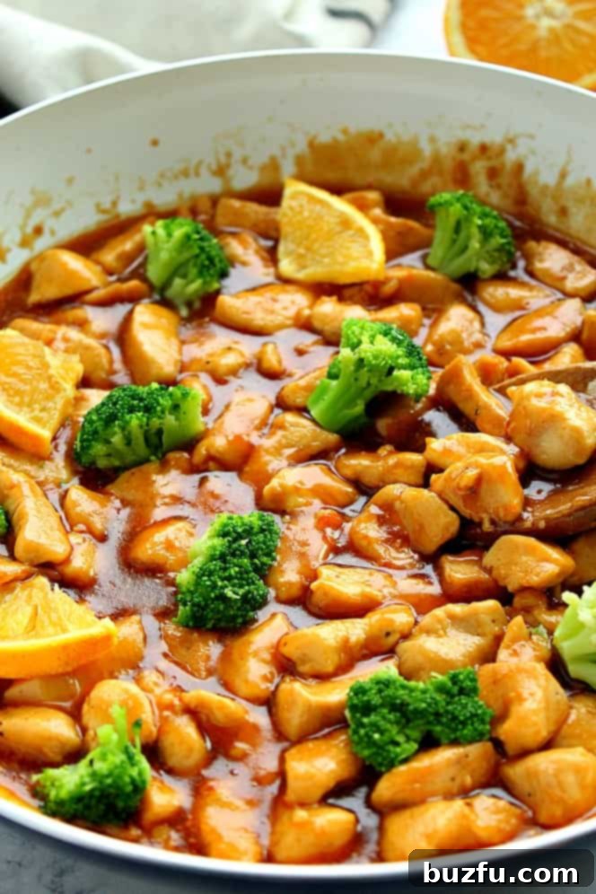 Orange chicken in sauce in a pan.