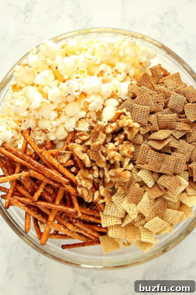 Overhead shot of all ingredients for the party mix laid out: popped popcorn, Chex cereal, pretzels, and walnuts.