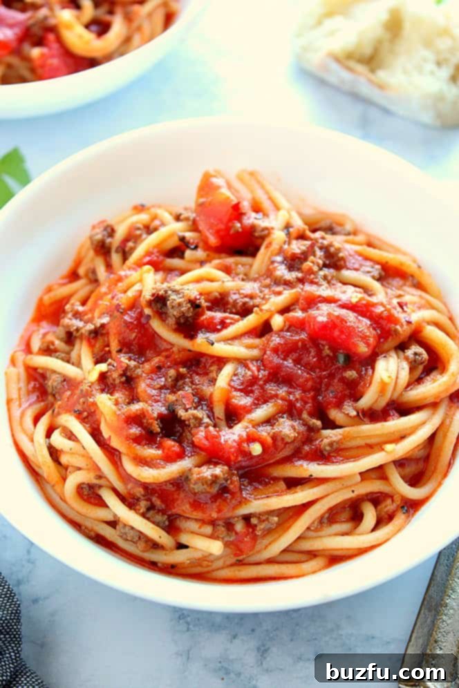 Delicious Instant Pot Spaghetti Served in a Bowl Spaghetti in a white pasta bowl on a marble board, garnished with fresh parsley.
