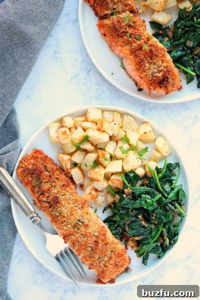 Overhead shot of two plates with crusted salmon, potatoes and spinach. 