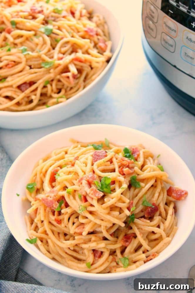 Side shot of two servings of Instant Pot Pasta Carbonara in white bowls, with the Instant Pot pressure cooker visible in the background.