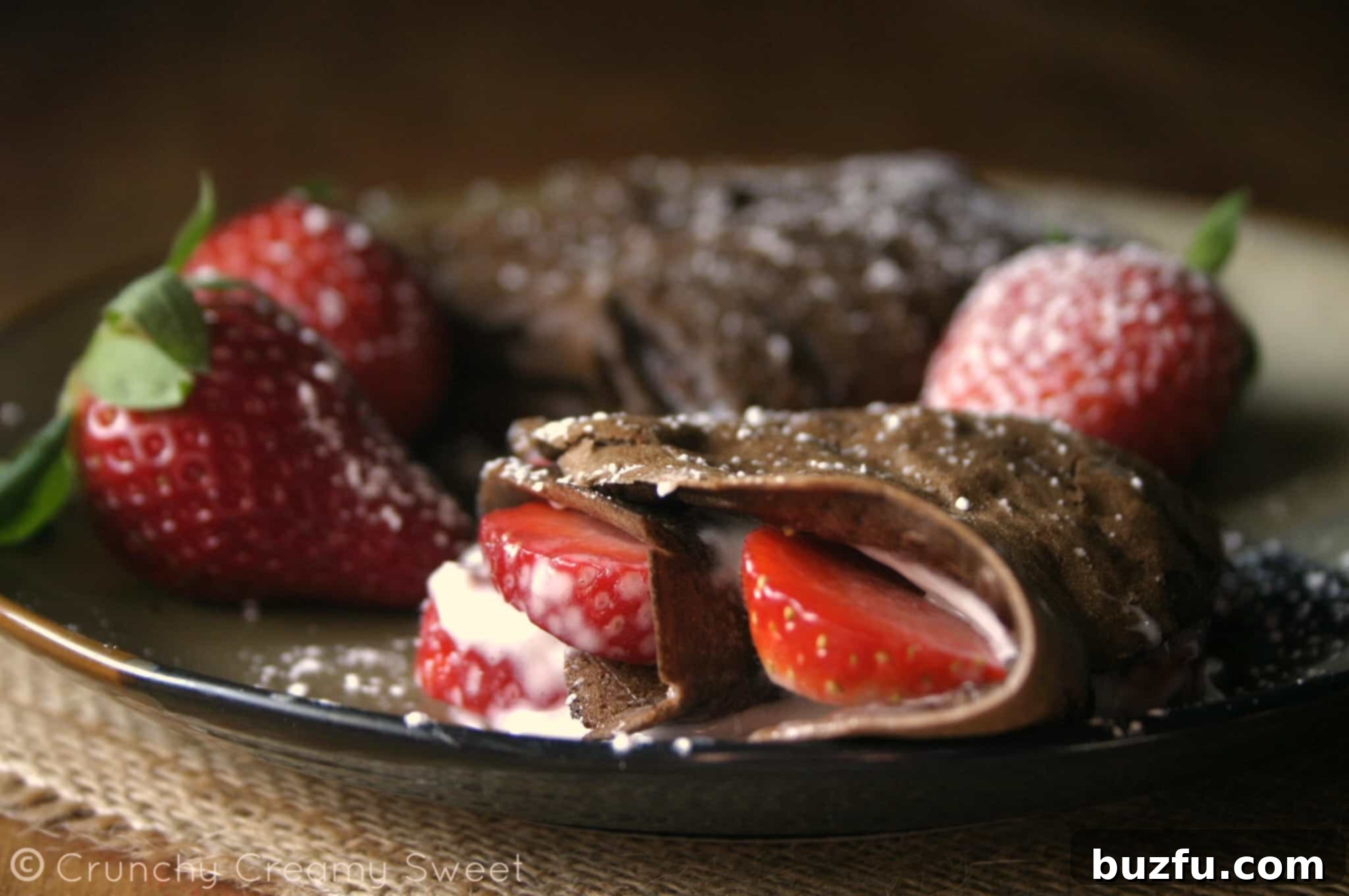 Single Chocolate Crepe with Strawberry and Cream Cheese Filling Closeup of a single chocolate crepe folded into a triangle, showing the strawberry and cream cheese filling, dusted with powdered sugar.