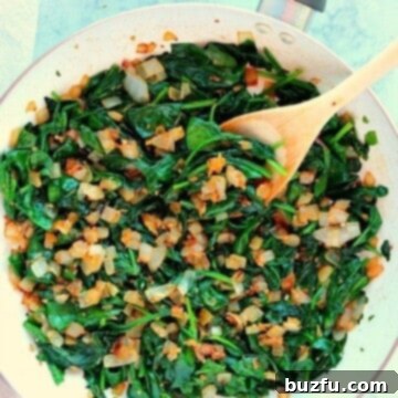 Sauteed spinach with onions in white skillet.
