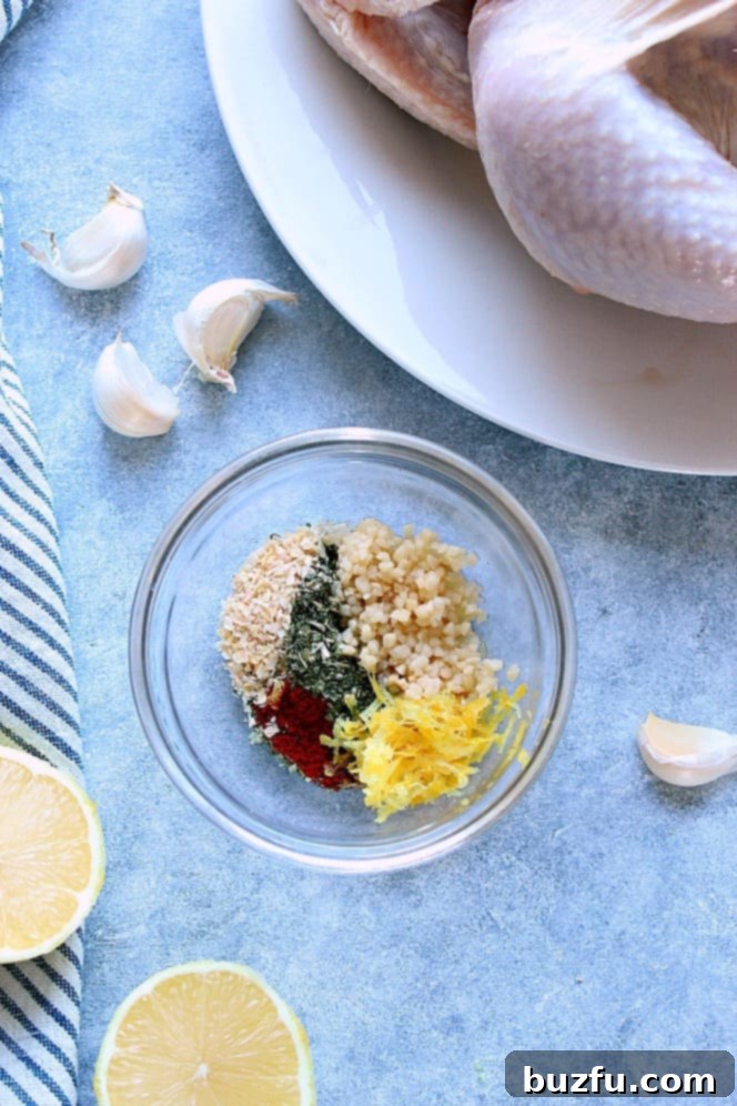 Overhead shot of seasoning mix in a small glass bowl, with whole chicken on plate in the background.