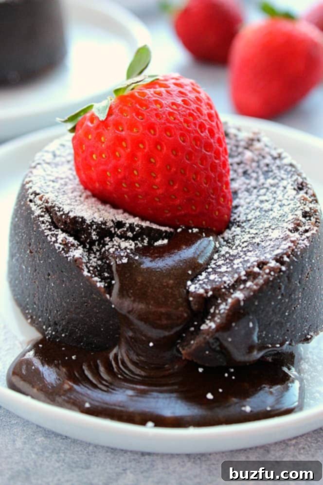 Instant Pot Chocolate Lava Cake Recipe - very easy and decadent molten lava cakes cooked in the Instant Pot pressure cooker, ready in less than 20 minutes. The gooey, fudgy center is irresistible! Close up shot of lava cake with gooey center, topped with strawberry.