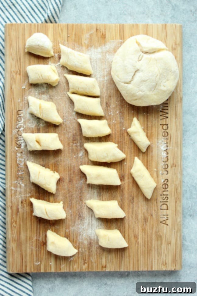 Overhead shot of perfectly cut Polish potato dumplings arranged on a wooden cutting board, showcasing their traditional angled shape.