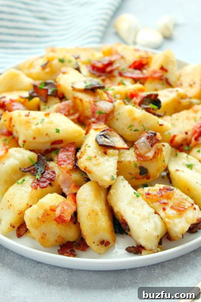 Side shot of Polish potato dumplings with crispy bacon and mushrooms on a white plate, ready to be enjoyed.