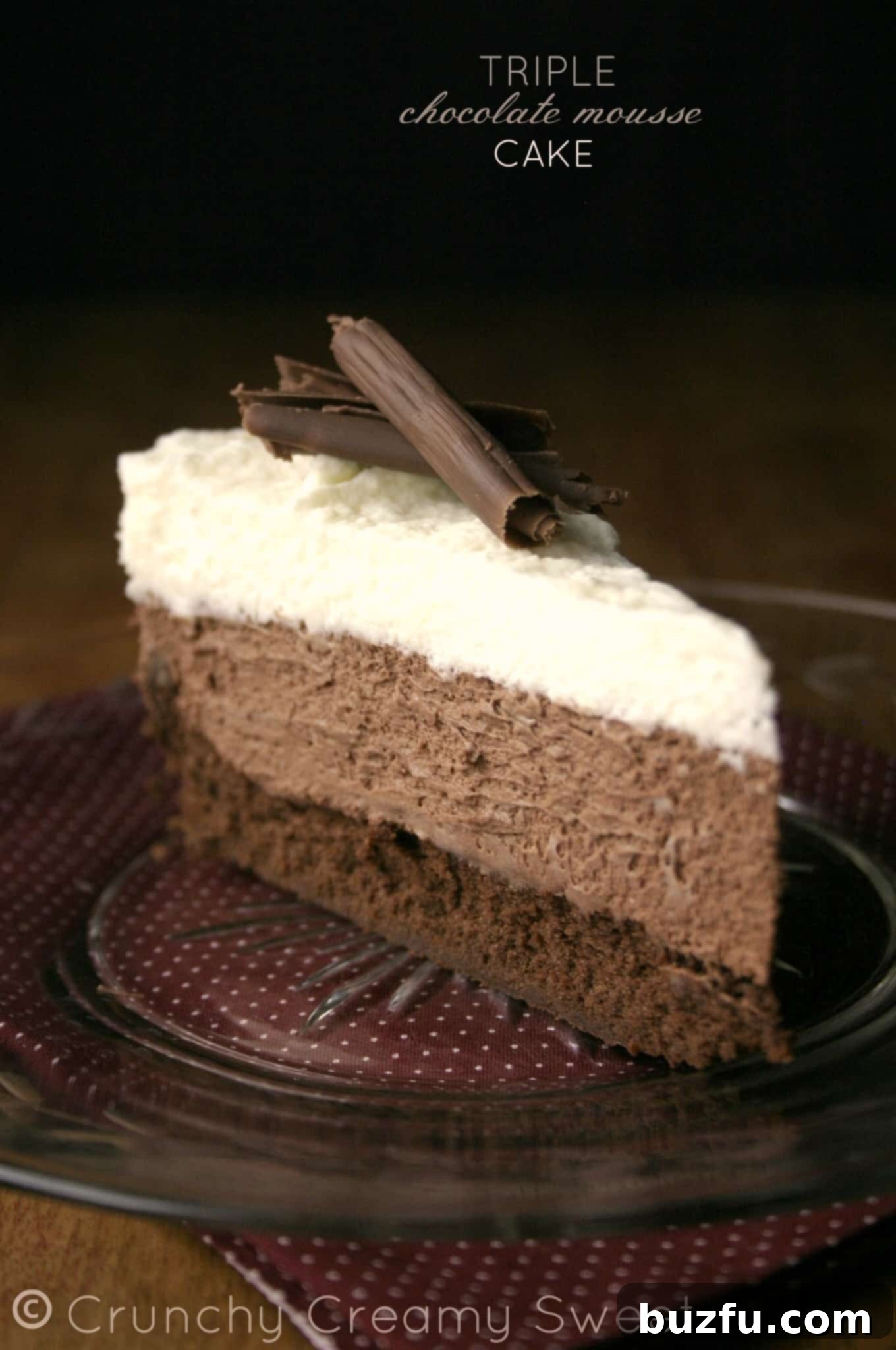 A perfectly sliced piece of Triple Chocolate Mousse Cake on an elegant glass plate, showcasing its distinct layers.