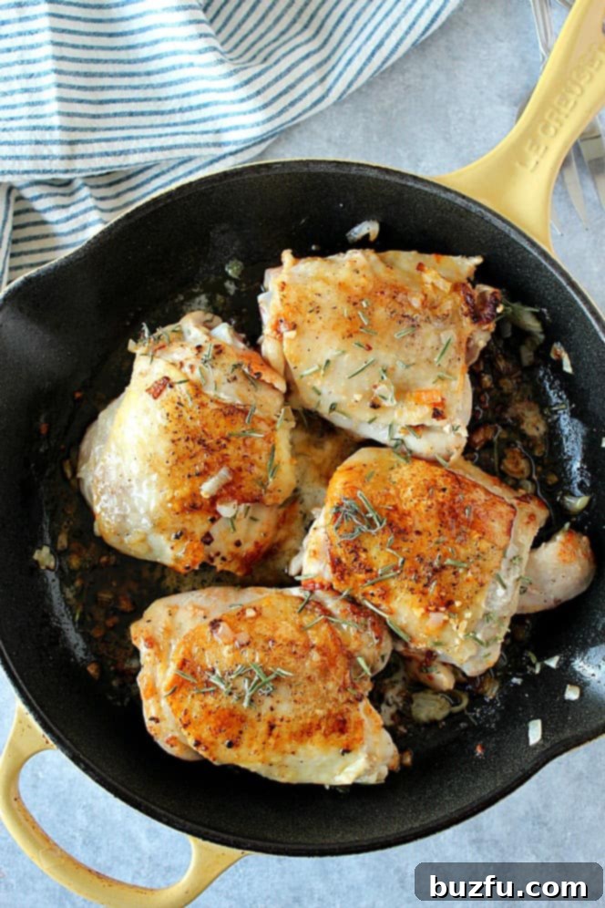 Overhead shot of 4 chicken thighs in cast iron skillet.