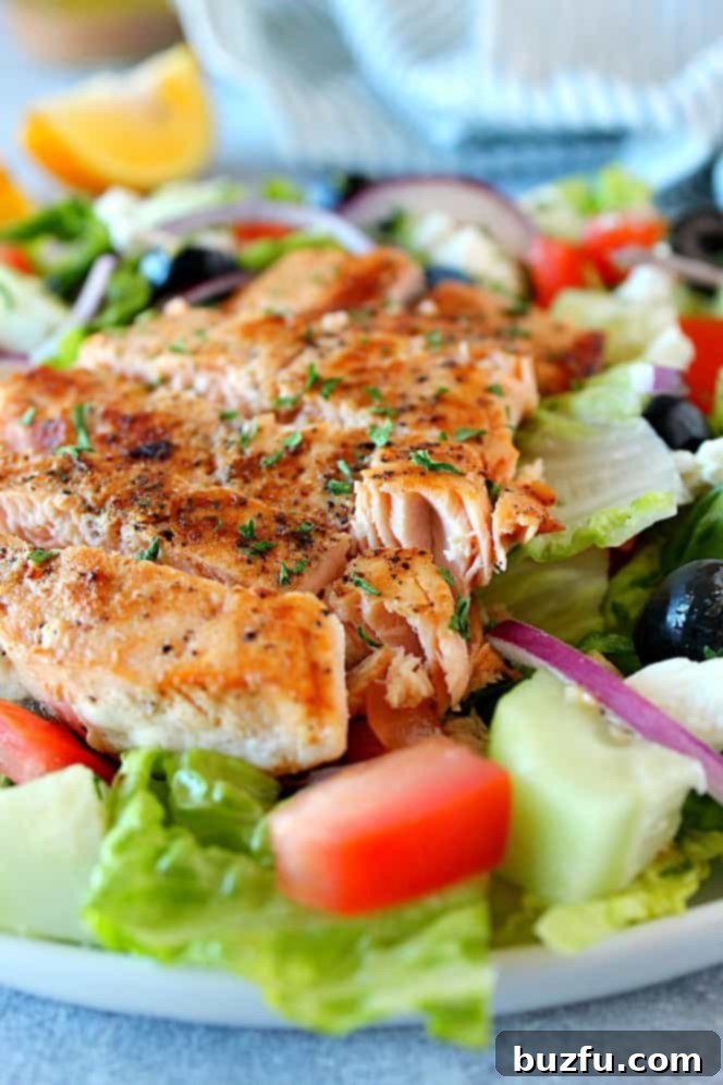 Side close up shot of Greek salmon salad on white plate, showcasing its vibrant ingredients.